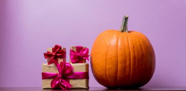 Bir Turuncu kabak ve hediye kutuları mor zemin üzerine. Görüntü yan köşe ışık ile