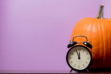 Bir Turuncu kabak ve mor zemin üzerine vintage çalar saat