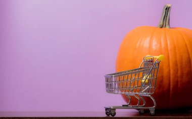 Bir Turuncu kabak ve mor zemin üzerine alışveriş sepeti