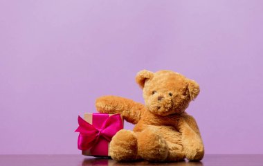 Vintage oyuncak ayı ve mor zemin üzerine hediye kutusu