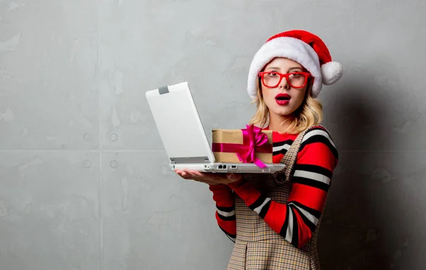 年轻女孩与笔记本电脑和圣诞礼品盒灰色背景 — 图库照片