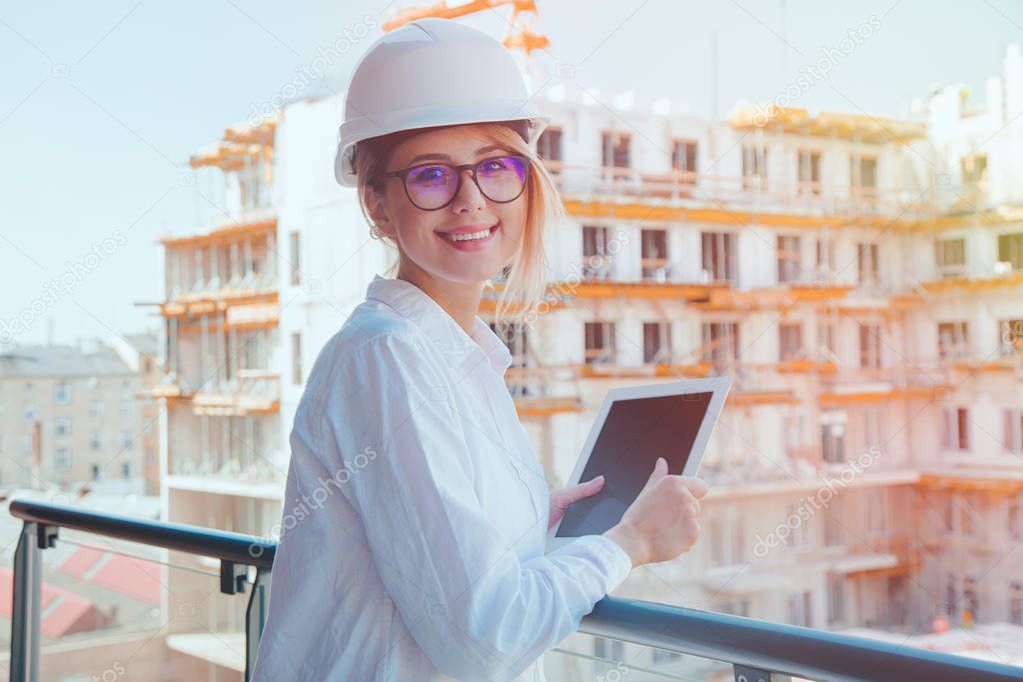 Young engineer woman with helmet and tablet on building construction site