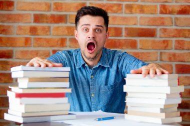 Genç adam bir tablo kitapları ile yorgun