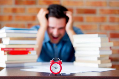 Kitap ve çalar saat ile tişörtlü genç adam