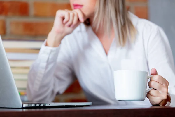 Woman on working place holding a cup of hot drink — Stock Photo, Image