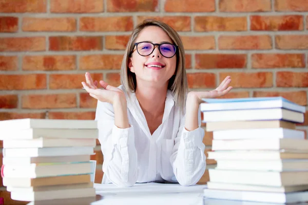 Frau mit Brille sitzt mit Büchern am Tisch — Stockfoto