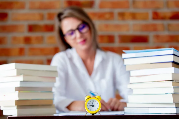 目覚まし時計とテーブルの上の本の女性 — ストック写真