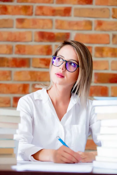 Frau mit Brille sitzt mit Büchern am Tisch — Stockfoto