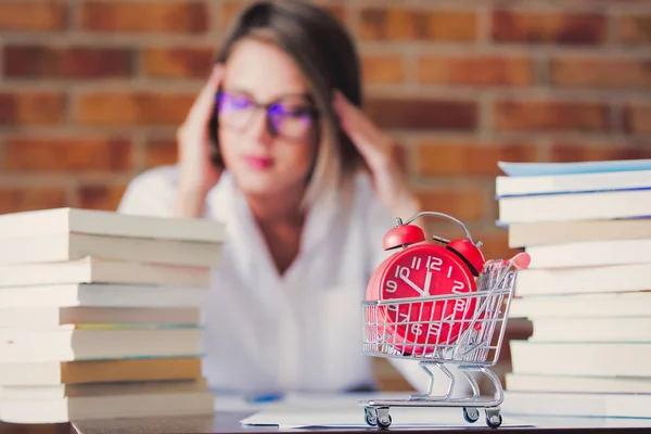 Mulher com livros e carrinho com despertador — Fotografia de Stock