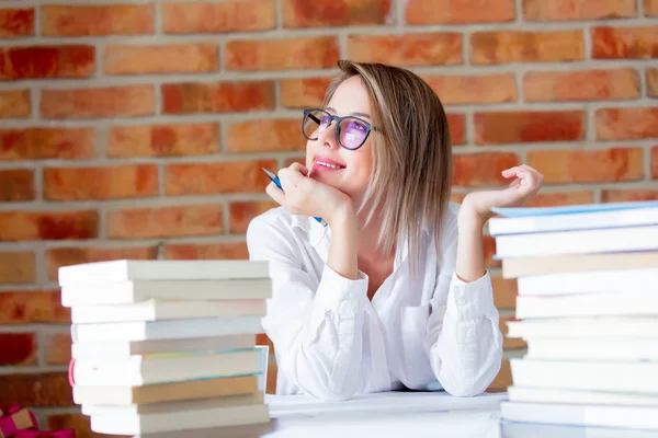 Kobieta w okularach siedzący przy stole z książek — Zdjęcie stockowe