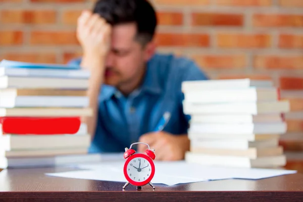 Jonge man in hemd met boeken en wekker — Stockfoto