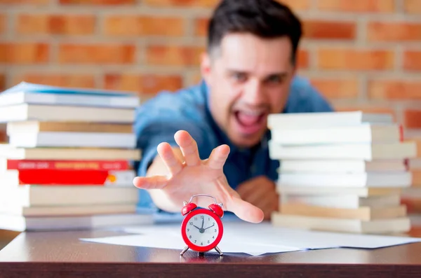 Young man in shirt with books and alarm clock — Stock Photo, Image