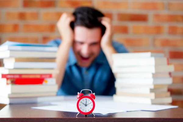 Jonge man in hemd met boeken en wekker — Stockfoto