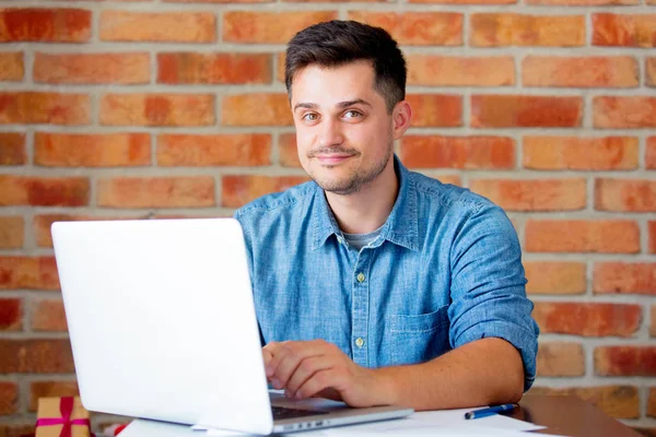 Jeune homme avec ordinateur portable sur le lieu de travail — Photo