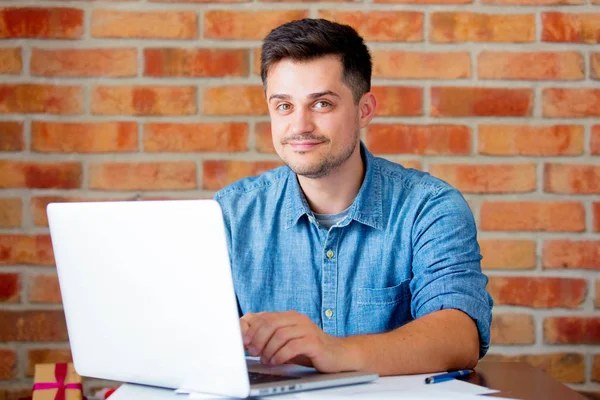 Jovem com computador portátil no local de trabalho — Fotografia de Stock