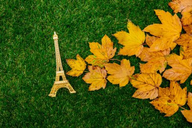Altın Sonbahar akçaağaç yaprağı ve Eyfel Kulesi Hatıra yeşil çimenlerin üzerinde. 