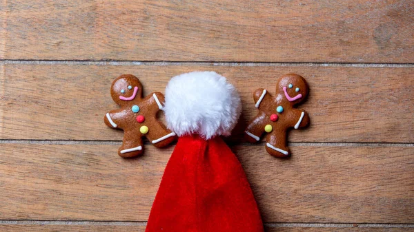 姜饼曲奇饼和圣诞老人帽子在木桌上 — 图库照片