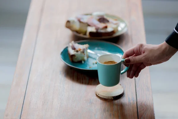 Hand holding cup near pate with eaten cake — Stock Photo, Image