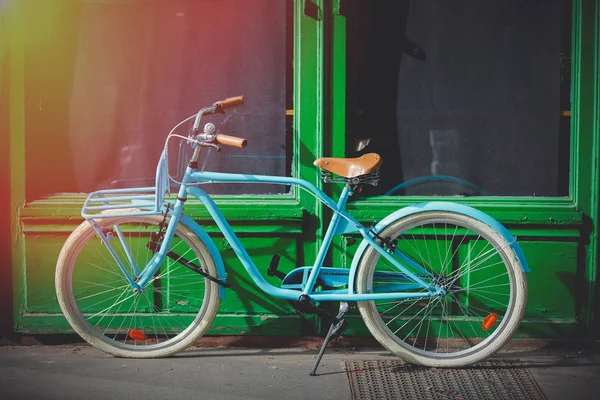 Old blue bike near green house on street — Stock Photo, Image