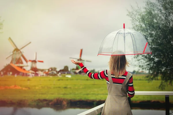 Chica estancia en un puente con molinos holandés — Foto de Stock
