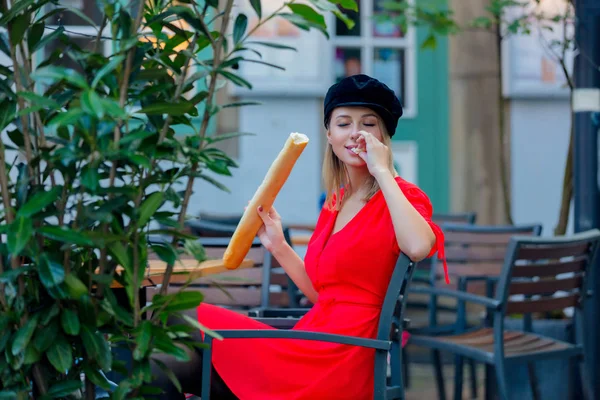 Kafede oturan baget ile kırmızı elbiseli Bayan — Stok fotoğraf