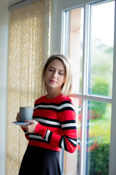 Menina com xícara de café ficar perto da janela — Fotografia de Stock