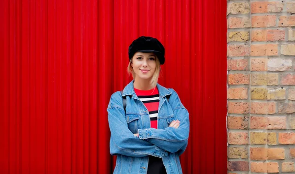 Ragazza in cappello e jeans giacca stare vicino alla porta rossa — Foto Stock