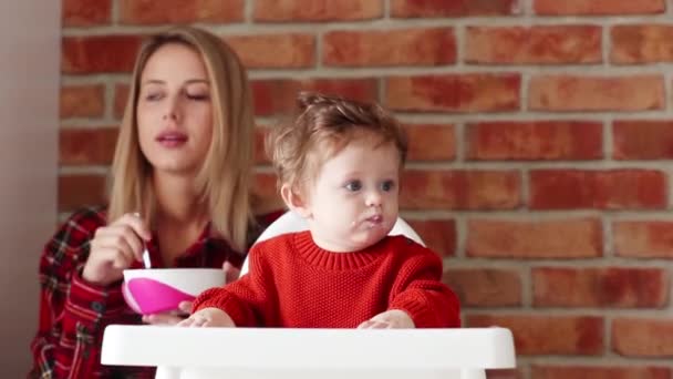 Jovem mãe alimentando uma criança com mingau de cereal — Vídeo de Stock