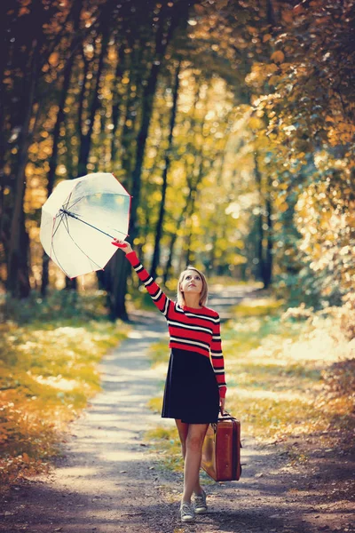 Menina com guarda-chuva e mala no parque de outono — Fotografia de Stock