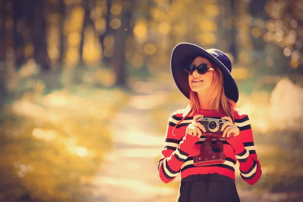 Menina de chapéu com uma câmera no parque de outono — Fotografia de Stock