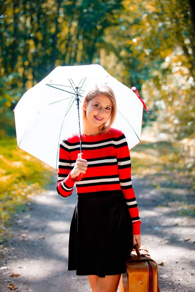Flicka med paraply och resväska i höst park — Stockfoto