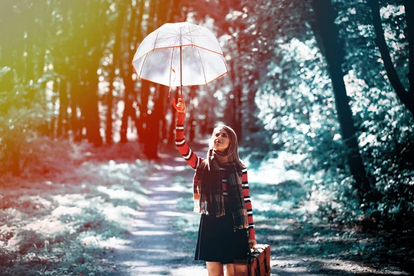 Ragazza con ombrellone e valigia nel parco autunnale — Foto Stock
