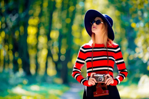 Ragazza in cappello con una fotocamera nel parco autunnale — Foto Stock