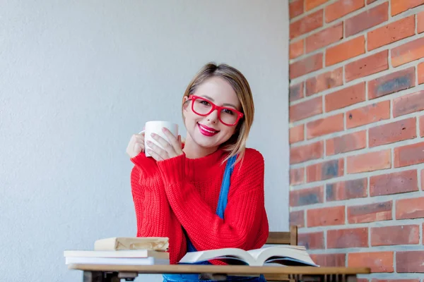 Fille souriante avec une tasse de café et des livres — Photo