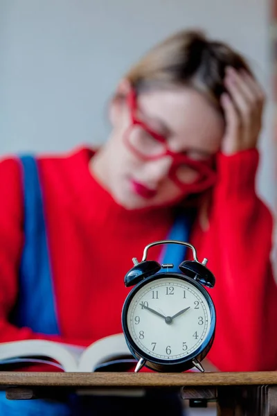 Ragazza stanca con libri e sveglia — Foto Stock