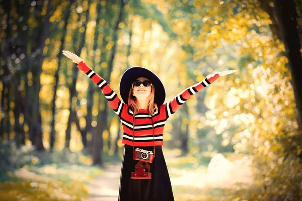 Ragazza in cappello con una fotocamera nel parco autunnale — Foto Stock