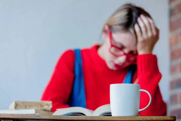 Chica cansada con taza de café y libros —  Fotos de Stock