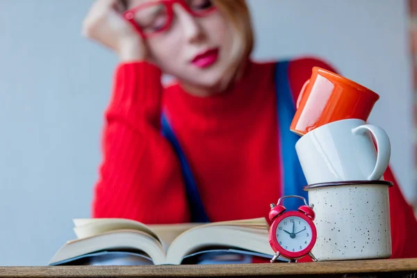 Moe meisje met kopjes koffie en boeken — Stockfoto