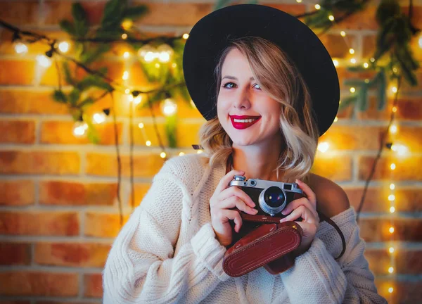 ビンテージ カメラ クリスマス ライト 松の枝の白いセーターに居心地の良い若い女性の肖像画 — ストック写真