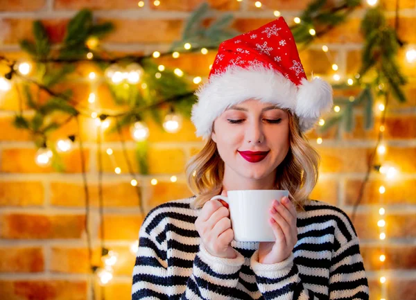 一杯のコーヒーとクリスマスの照明と松の枝と居心地の良い若い女性の肖像 — ストック写真