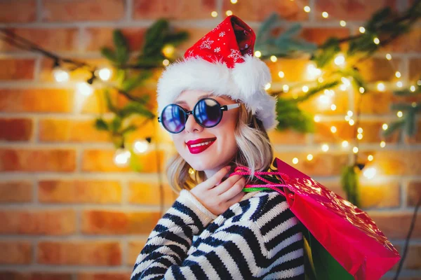 ショッピング バッグ クリスマス ライトの背景に松の枝と居心地の良い若い女性の肖像画 — ストック写真