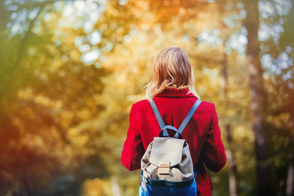 秋季季节公园有红大衣和 Packpack 的年轻女子 后侧视图 — 图库照片