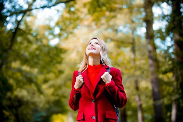 赤いコートおよび Packpack 秋公園内の若い女性 — ストック写真