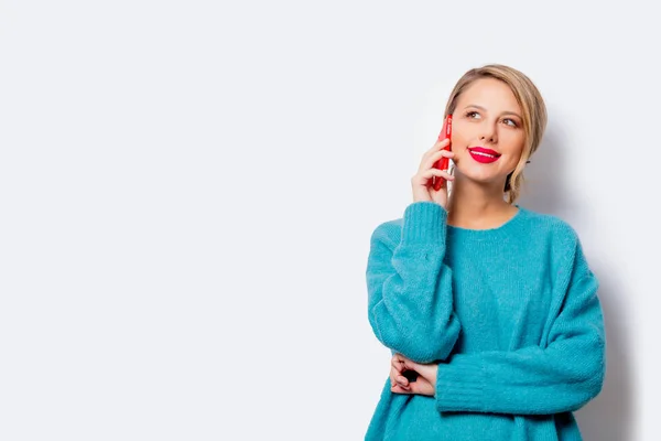 白い背景の分離上の携帯電話に青いセーターの美しい白い笑顔の女性の肖像画 — ストック写真