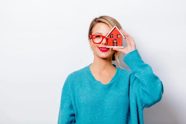 Portrait of a beautiful white smiling woman in blue sweater with dream house on white background, isolated.