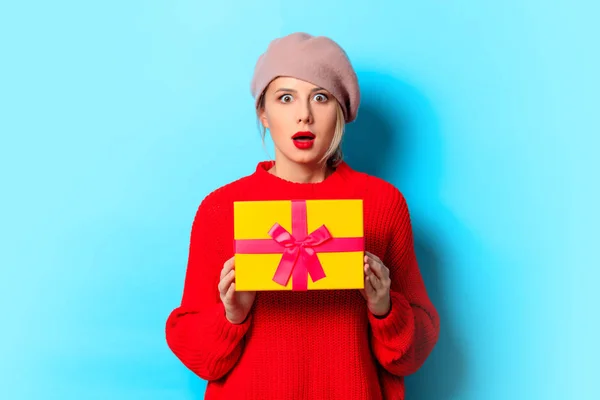 一个年轻女孩的肖像与礼品盒在蓝色背景红色毛衣 — 图库照片