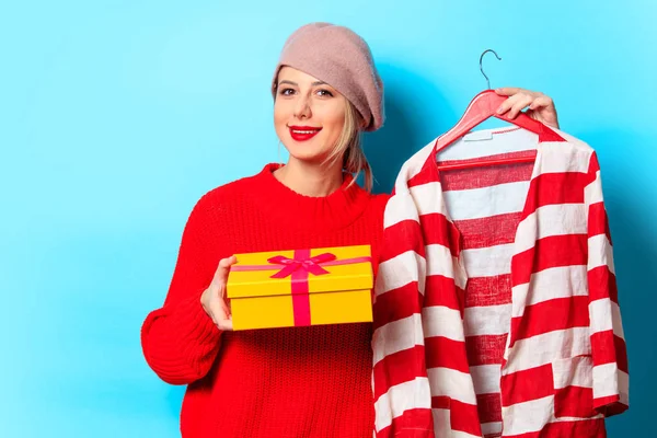 一个年轻女孩的肖像在红色毛衣与礼品盒和夹克在蓝色背景 — 图库照片