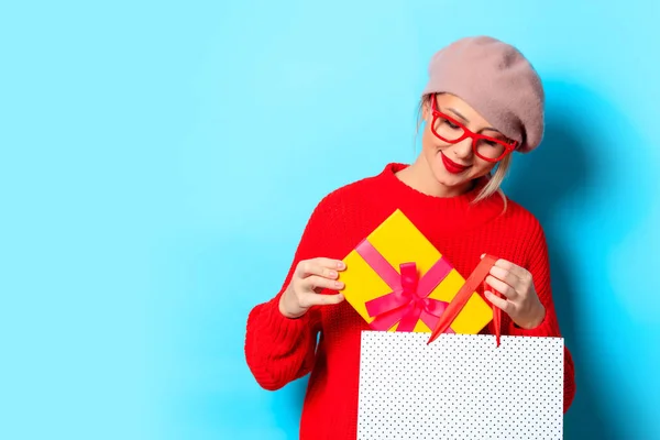 ギフト ボックス 青の背景にショッピング バッグと赤いセーターの少女の肖像画 — ストック写真