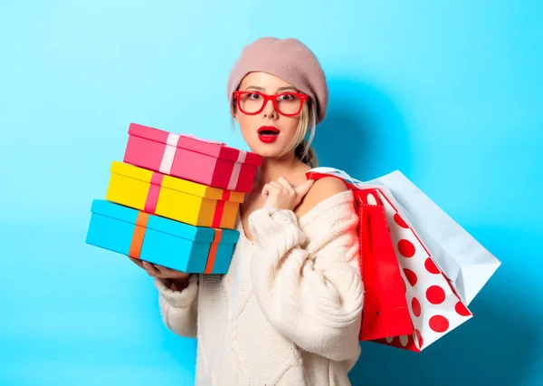 ギフト ボックスとショッピング バッグ青の背景に白のセーターの少女の肖像画 — ストック写真