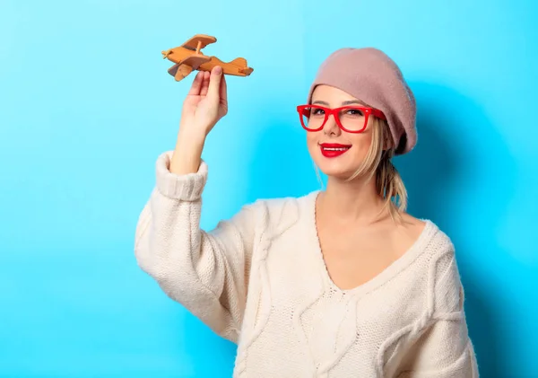 青の背景に木製のおもちゃの飛行機の白セーターの少女の肖像画 — ストック写真